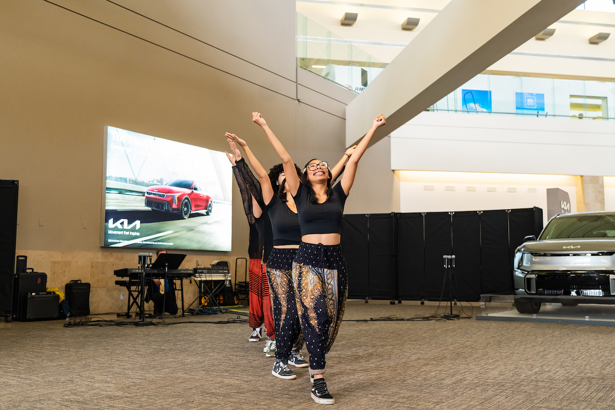 Student dancers line up and raise their arms as part of their dance.
