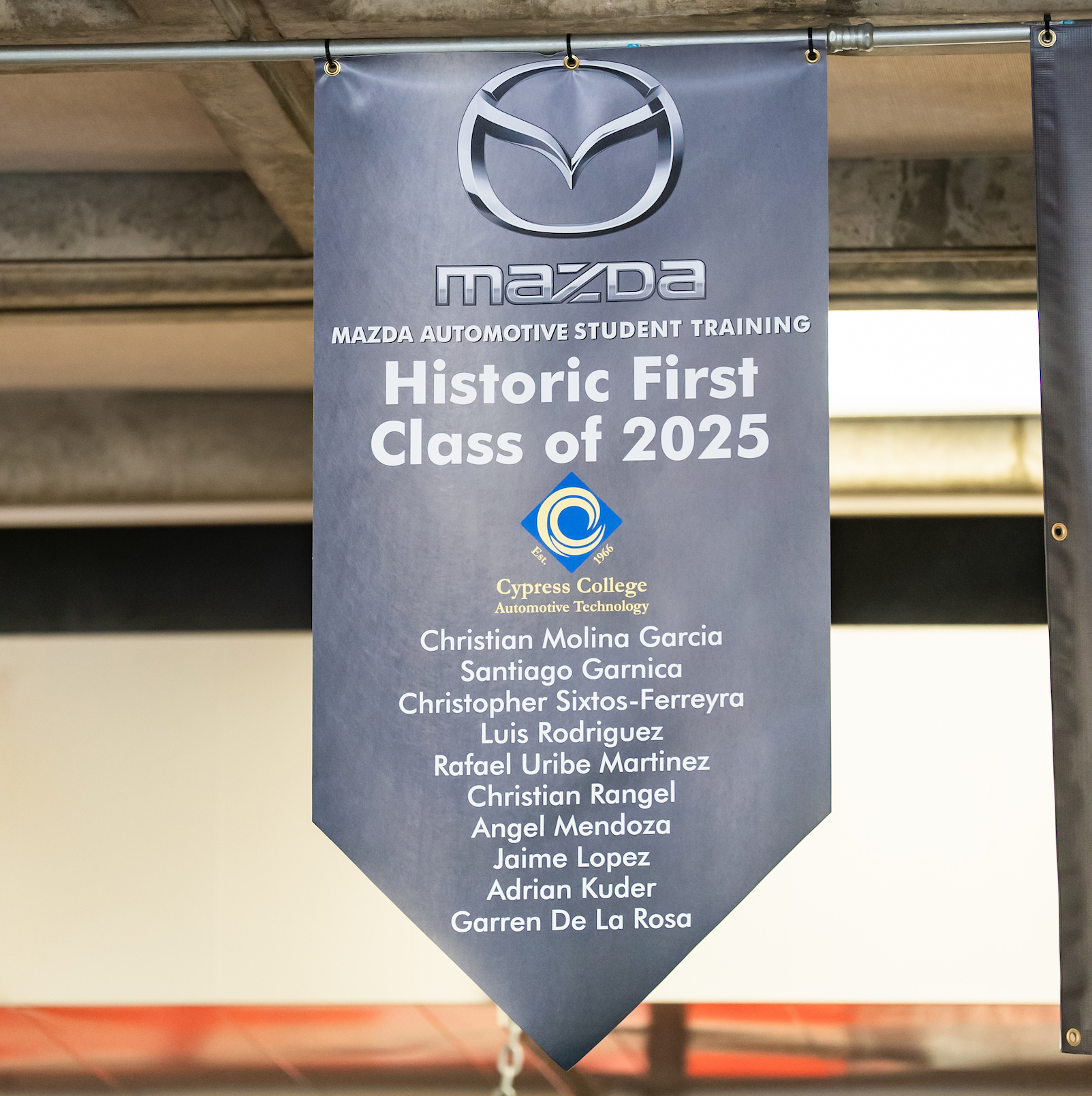 A banner reflects the names of the first 10 students to graduate under the Mazda/MAST partnership at Cypress College.