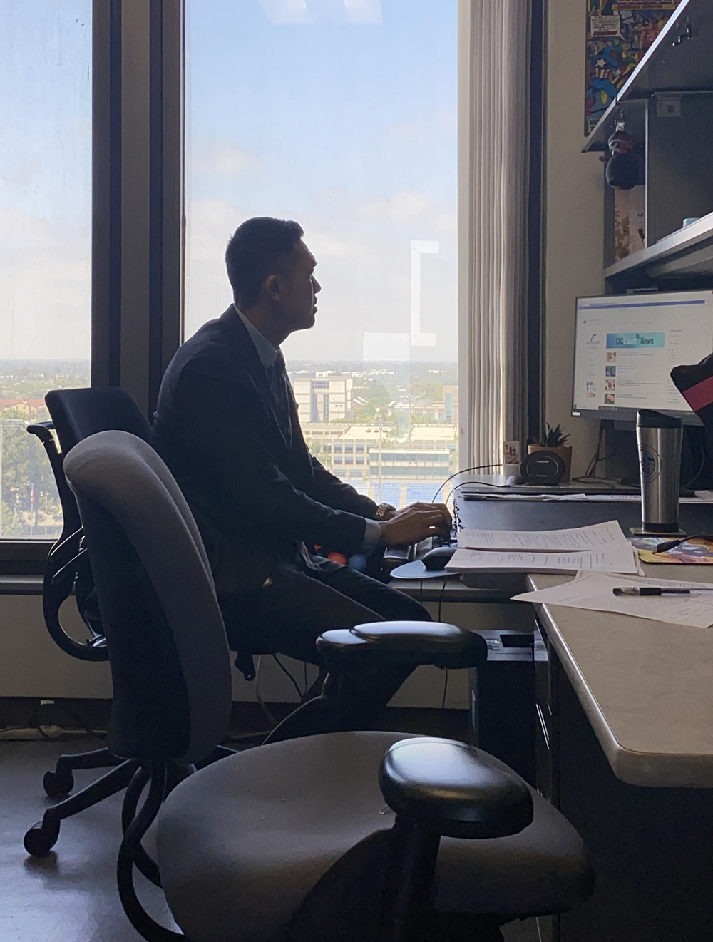 The silhouette of a man who sits in profile in a high-rise office.