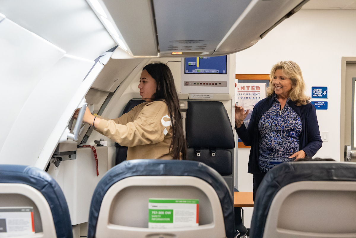 A student opens a simulated airplane cabin door