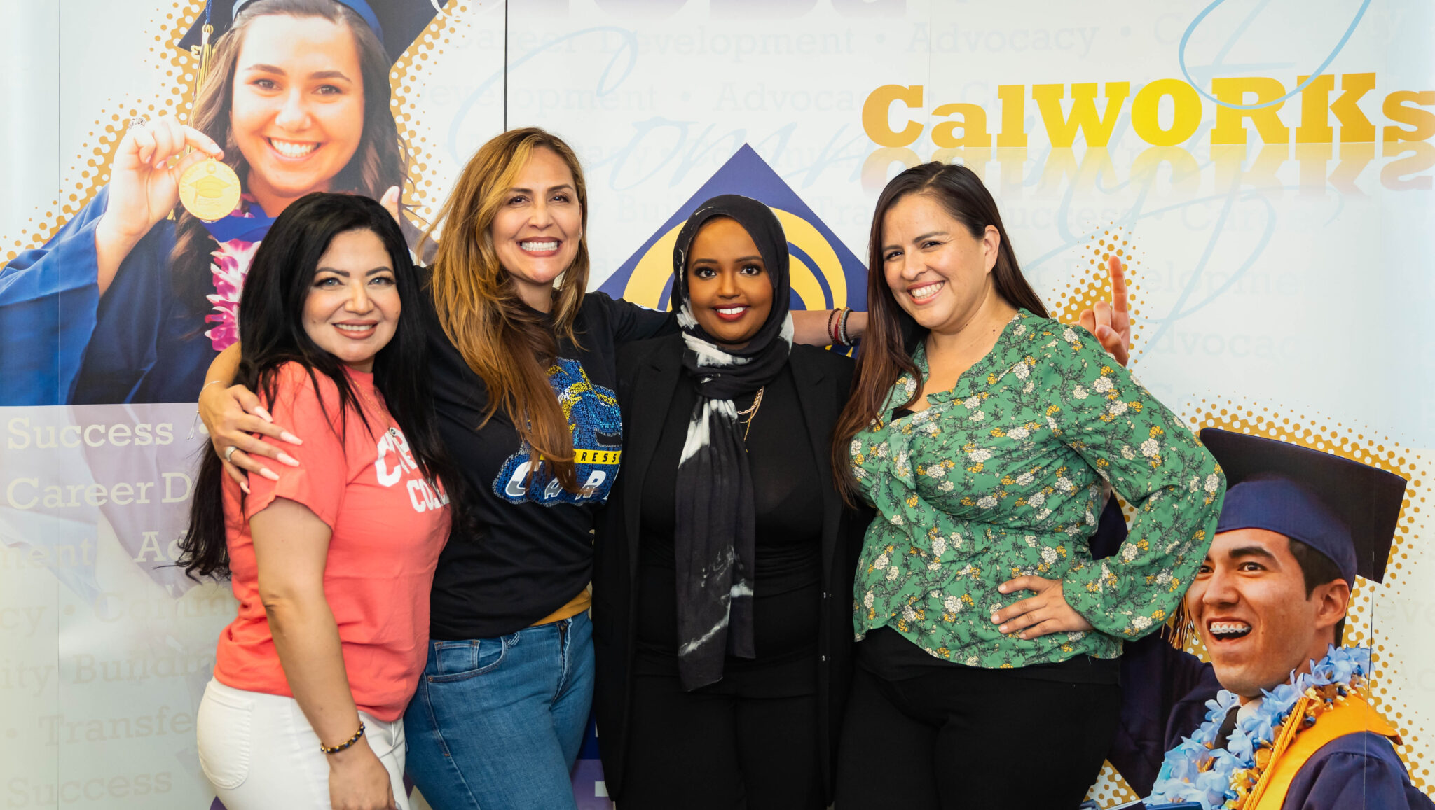 Quresh Jama poses with staff from the EOPS office in front of a CalWORKS banner.