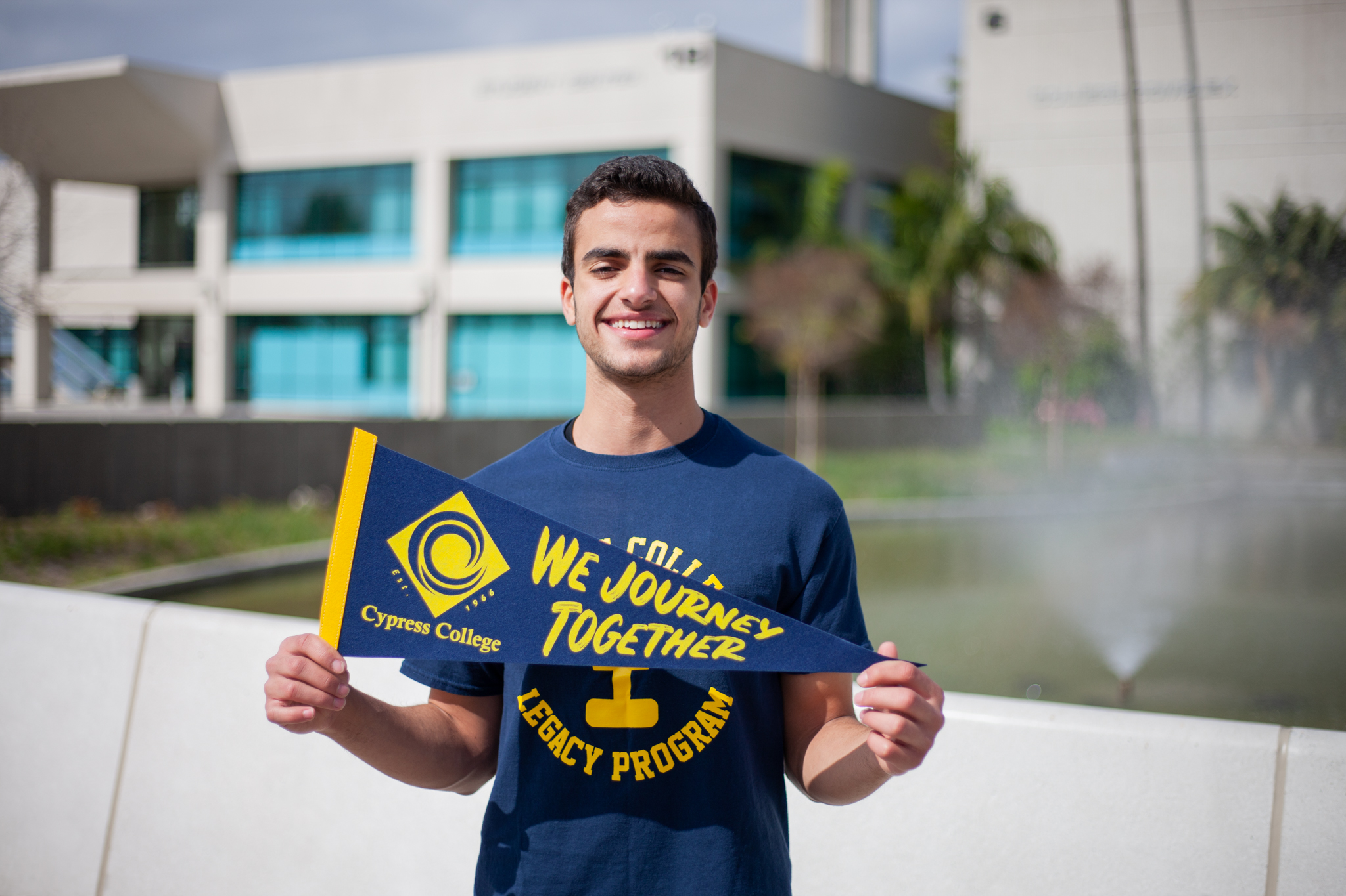 Student Jonathan Gad poses in Legacy Program T-shirt in front of pond on Cypress College campus. 