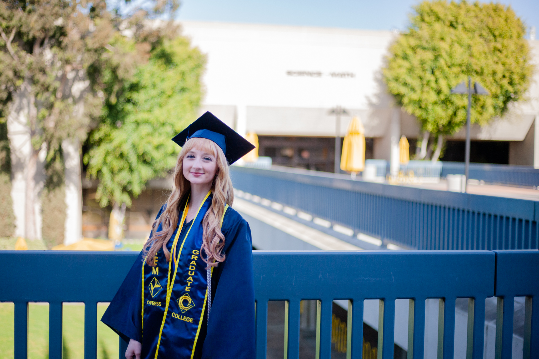 Lia Thompson poses on piazza in front of SEM building wearing graduation regalia. 