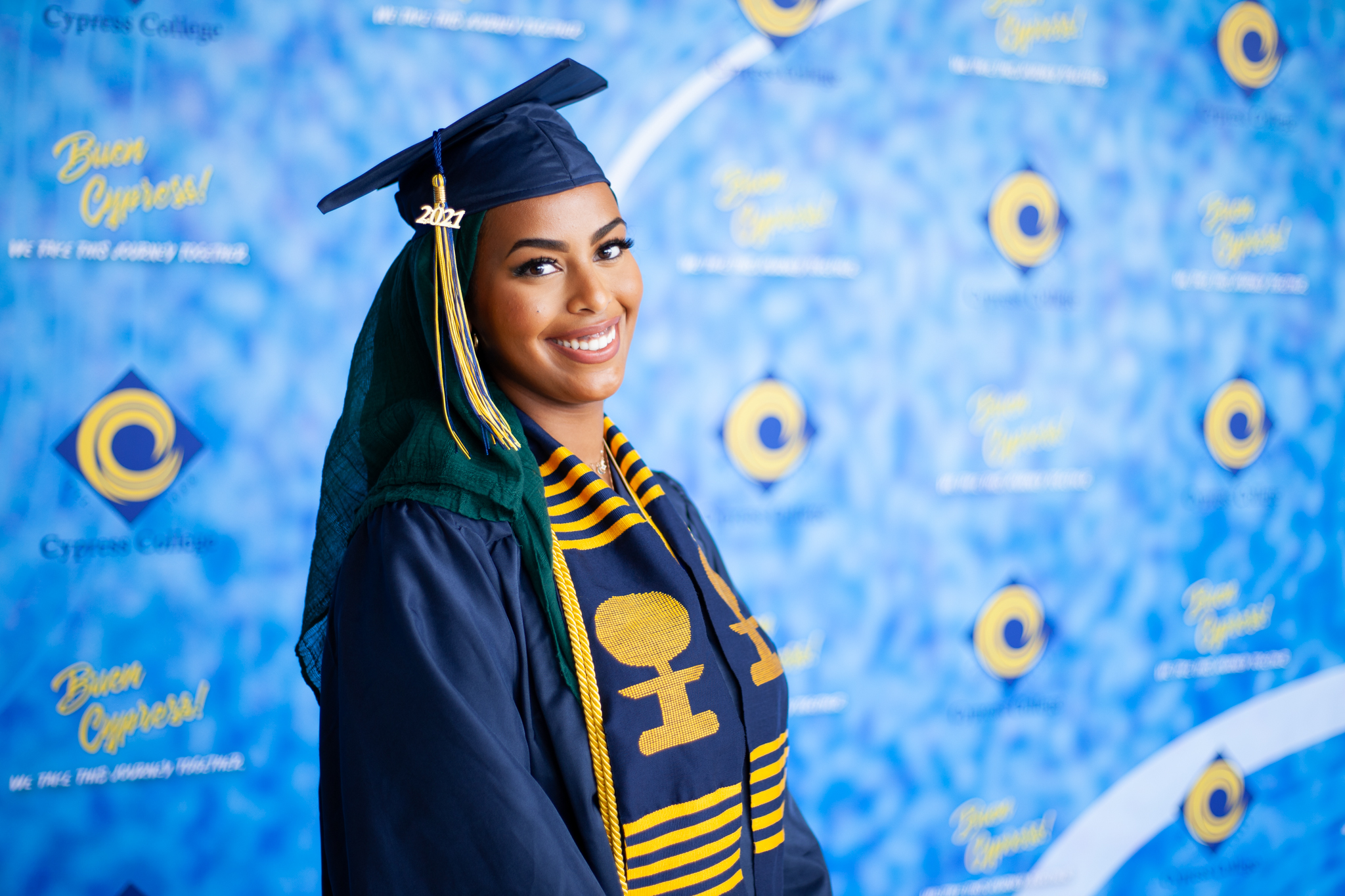 Counseling student Ayah Said poses in front of blue background with Legacy Program sash. 