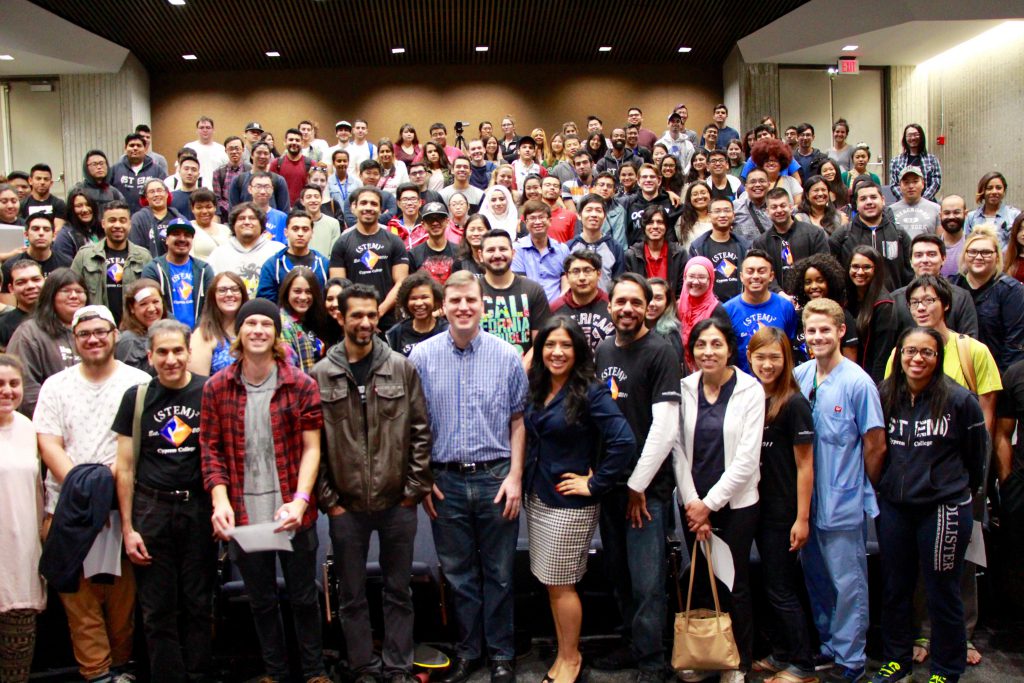A large group of STEM students smile at camera