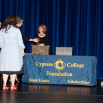 Foundation Office staff standing on stage around the Cypress College Foundation table.