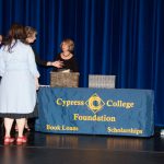 Foundation Office staff standing on stage around the Cypress College Foundation table.