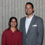 Young woman in glasses and red shirt with young man in glasses and grey suit.