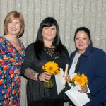 Dr. Schilling with two young ladies holding sunflowers.