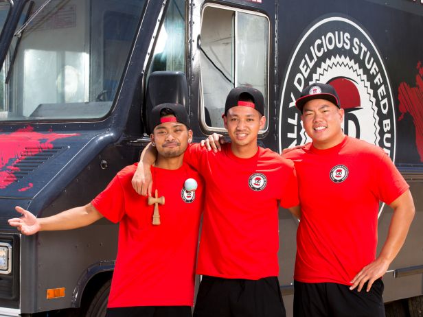 Three men in red t-shirts and black hats next to food truck