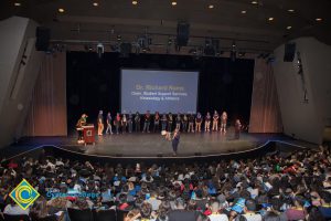 Dr. Richard Rams on stage speaking to a theater full of students while other presenters stand behind him at the 2018 Connect2Careers & Majors2Careers event.