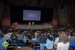 Two women in green t shirts and brown pants and another woman in a black shirt and brown pants speaks to a audience at the 2018 Majors2Careers & Connect2Cypress event.