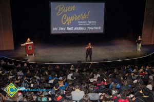 Audience listening to speakers on stage at the 2018 Connect2Cypress & Majors2Careers with a large screen with the words Buen Cypress We Take this Journey Together projected on it.